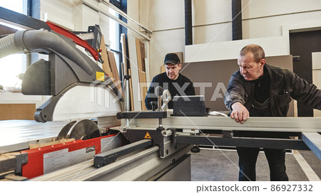 Your project is our business. Sawing up of a wooden board on a sliding table saw. Woodworking and carpentry production. Furniture manufacture. 86927332