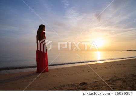 Young woman relaxing alone on ocean sand shore by seaside enjoying warm tropical evening. 86929894