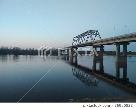 a bridge across the river in the evening with stones in the foreground. urban evening landscape 86930828