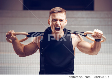 Athlete gymnast in the gym in training with gymnastic rings 86930903