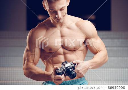 Old-fashioned camera in the hands of a muscular young cameraman 86930908