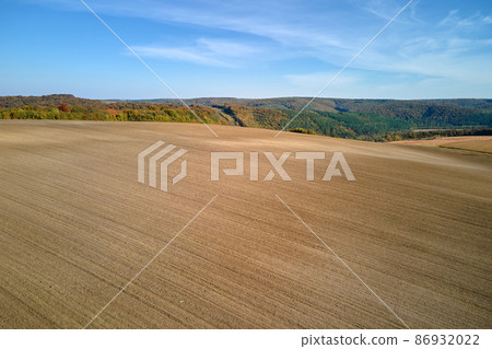 Aerial view of plowed agricultural field with cultivated fertile soil prepared for planting crops in spring Aerial view of plowed agricultural field with cultivated fertile soil prepared for planting crops in spring 86932022