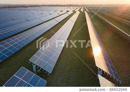 Aerial view of large sustainable electrical power plant with rows of solar photovoltaic panels for producing clean electric energy in evening. Concept of renewable electricity with zero emission Aerial view of large sustainable electrical power plant with rows of solar photovoltaic panels for producing clean electric energy in evening. Concept of renewable electricity with zero emission 86932049
