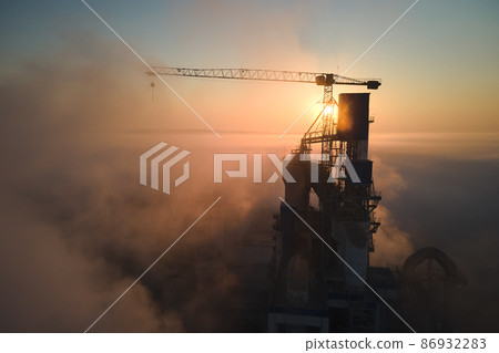 Aerial view of cement factory with high concrete plant structure and tower crane at industrial production site on foggy morning. Manufacture and global industry concept. 86932283