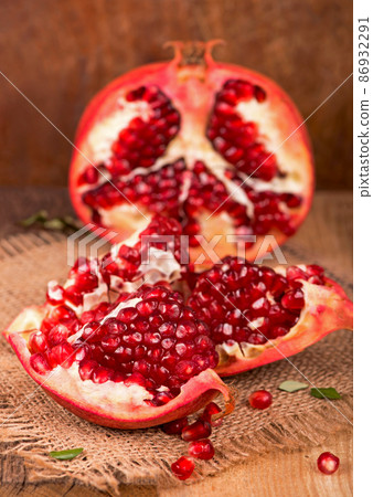 Juicy pomegranate and its half Beautiful composition with juicy pomegranates, on old wooden table 86932291