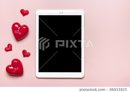 tablet for chooses gifts, makes purchase, two red hearts on pink table Top view Flat lay Holiday shopping list, Happy Valentine's day, party, online shop concept Mock up 86933925