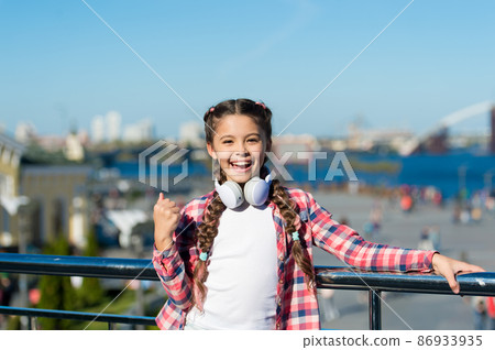 Girl child listen music outdoors with modern headphones. 86933935