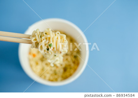 instant noodles with wooden chopsticks on a blue background, top view. Korean national dish. instant noodles with wooden chopsticks on a blue background, top view. Korean national dish. 86934584