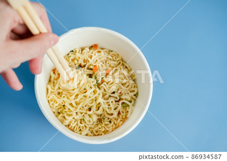 instant noodles with wooden chopsticks on a blue background, top view. Korean national dish. instant noodles with wooden chopsticks on a blue background, top view. Korean national dish. 86934587