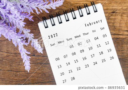 February 2022 desk calendar with flower on wooden background. 86935631
