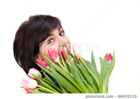 Portrait of a brunette with a beautiful smile with a bouquet of bright fresh tulips, isolated, white background Portrait of a brunette with a beautiful smile with a bouquet of bright fresh tulips, isolated, white background 86938319