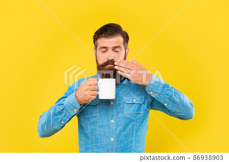 Serious caucasian man with closed eyes smelling coffee holding hot cup yellow background Serious caucasian man with closed eyes smelling coffee holding hot cup yellow background 86938903