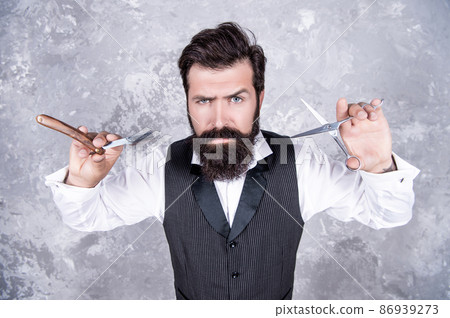 handsome brutal man barber with beard hold barbershop retro razor blade and scissors, hair salon. 86939273