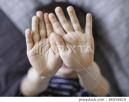 Little boy covers his face with hands. Child refuses to be photographed. Playful kid shows his palm hands instead of laughing face. Little boy covers his face with hands. Child refuses to be photographed. Playful kid shows his palm hands instead of laughing face. 86939929