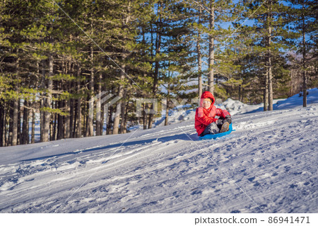happy and positive little boy enjoying sledding and cold weather outdoor, winter fun activity concept 86941471