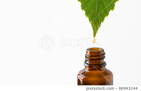Oil drop dripping from leaf to bottle isolated on white background. Herbal alternative medicine or natural skin care cosmetics concept. 86943244