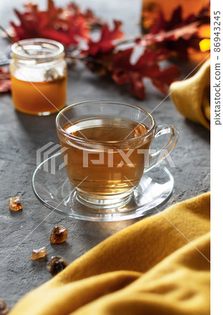 A glass cup of tea with honey on gray table. 86943245