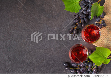 Glasses of red wine and blue grape on black background top view. Glasses of red wine and blue grape on black background top view. 86943306