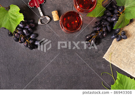 Glasses of red wine and blue grape on black background top view. Glasses of red wine and blue grape on black background top view. 86943308