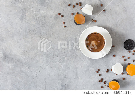 Espresso coffee capsules and coffee cup on grey background top view. Espresso coffee capsules and coffee cup on grey background top view. 86943312