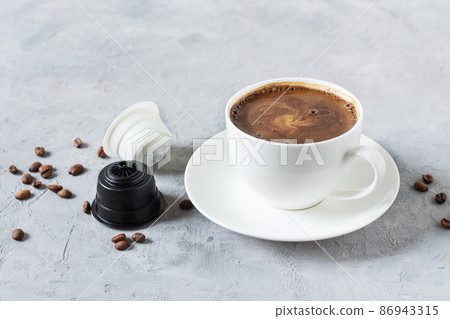 Espresso coffee capsules and coffee cup on grey background. Espresso coffee capsules and coffee cup on grey background. 86943315