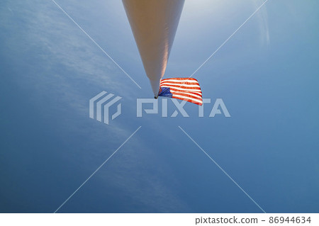 Looking up the America flag swinging on a pole 86944634