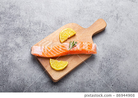 Raw salmon fish fillet with lemon wedges and rosemary on wooden cutting board Raw salmon fish fillet with lemon wedges and rosemary on wooden cutting board 86944908