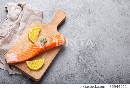 Raw salmon fish fillet with lemon wedges and rosemary on wooden cutting board Raw salmon fish fillet with lemon wedges and rosemary on wooden cutting board 86944921