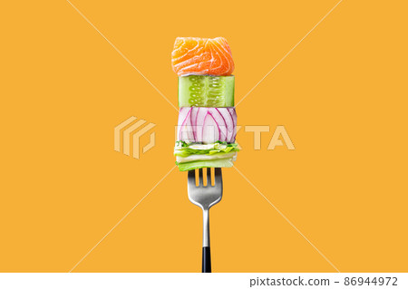 fork with food on it: delicious fillet salmon, cucumber, onion, green salad on orange background 86944972