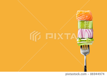 fork with food on it: delicious fillet salmon, cucumber, onion, green salad on orange background 86944974