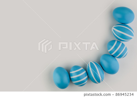 Corner border of blue striped Easter eggs over a light background.  86945234