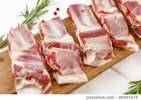 Raw meat ribs on wooden board on white background 86945474