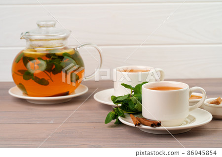 Black tea served with cinnamon sticks and mint on brown table 86945854