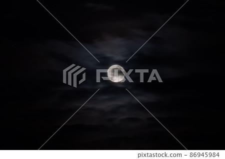 Moon rising against black sky with clouds at night 86945984