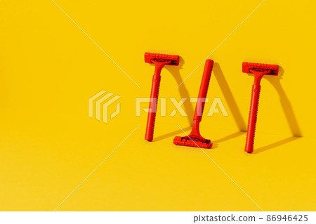 Disposable razors on yellow background, studio shot Disposable razors on yellow background, studio shot 86946425