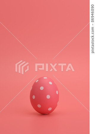 A pink painted Easter egg in white peas stands on a pink background.  86946890