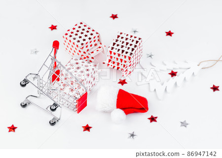 Christmas and New Year background.Supermarket trolley with New Year's gifts on a light background. Christmas and New Year background.Supermarket trolley with New Year's gifts on a light background. 86947142