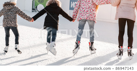 Soft,Selective focus.Winter sport.Learning how to skating on ice.Group of teenage friends ice skating on an ice rink.Enjoying winter outdoor activities.Outdoor. Soft,Selective focus.Winter sport.Learning how to skating on ice.Group of teenage friends ice skating on an ice rink.Enjoying winter outdoor activities.Outdoor. 86947143