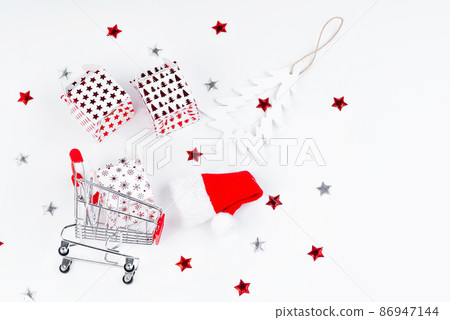 Christmas and New Year background.Supermarket trolley with New Year's gifts on a light background. Christmas and New Year background.Supermarket trolley with New Year's gifts on a light background. 86947144