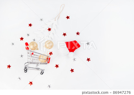 Christmas composition. Christmas and New Year background.Trolley from a supermarket with New Year's gifts and New Year's toys on a light background.Flat lay, top view, wide banner. Christmas composition. Christmas and New Year background.Trolley from a supermarket with New Year's gifts and New Year's toys on a light background.Flat lay, top view, wide banner. 86947276