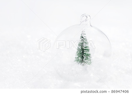 Shiny background.copy space.Greeting card, banner, poster.Soft focus.Shiny, glass Christmas ball with a miniature Christmas tree on the snow on a light background.Christmas composition. Shiny background.copy space.Greeting card, banner, poster.Soft focus.Shiny, glass Christmas ball with a miniature Christmas tree on the snow on a light background.Christmas composition. 86947406