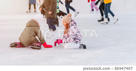 Soft,Selective focus.Funny moment fell on the ice skating rink.A kids takes relax after his fall while skating. Holiday and seasonal concept.Group of teenage friends ice skating on an ice rink. Soft,Selective focus.Funny moment fell on the ice skating rink.A kids takes relax after his fall while skating. Holiday and seasonal concept.Group of teenage friends ice skating on an ice rink. 86947407