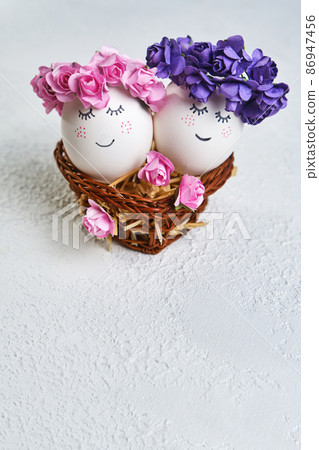 Two cuddling Easter eggs with sweet faces in floral spring wreaths Two cuddling Easter eggs with sweet faces in floral spring wreaths 86947456