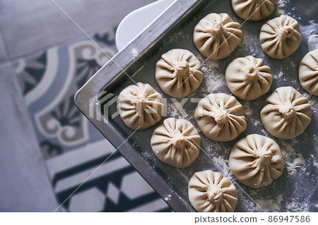 Pile of homemade raw khinkali delicious Georgian dumplings on home kitchen table Pile of homemade raw khinkali delicious Georgian dumplings on home kitchen table 86947586