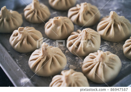 Pile of homemade raw khinkali delicious Georgian dumplings on home kitchen table Pile of homemade raw khinkali delicious Georgian dumplings on home kitchen table 86947587