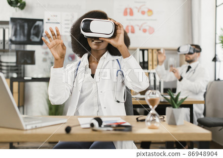 Two multicultural male and female doctors using VR goggles 86948904