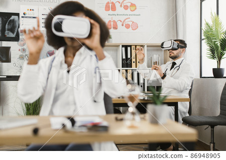 Two multicultural male and female doctors using VR goggles 86948905