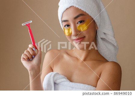 Asian young woman with patches under eyes holding razor 86949010