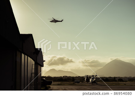 Hangar with helicopters at sunset. 86954080