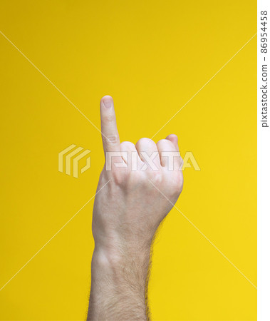 man hand with palm in fist and little finger straight up on yellow background. man hand with palm in fist and little finger straight up on yellow background. 86954458
